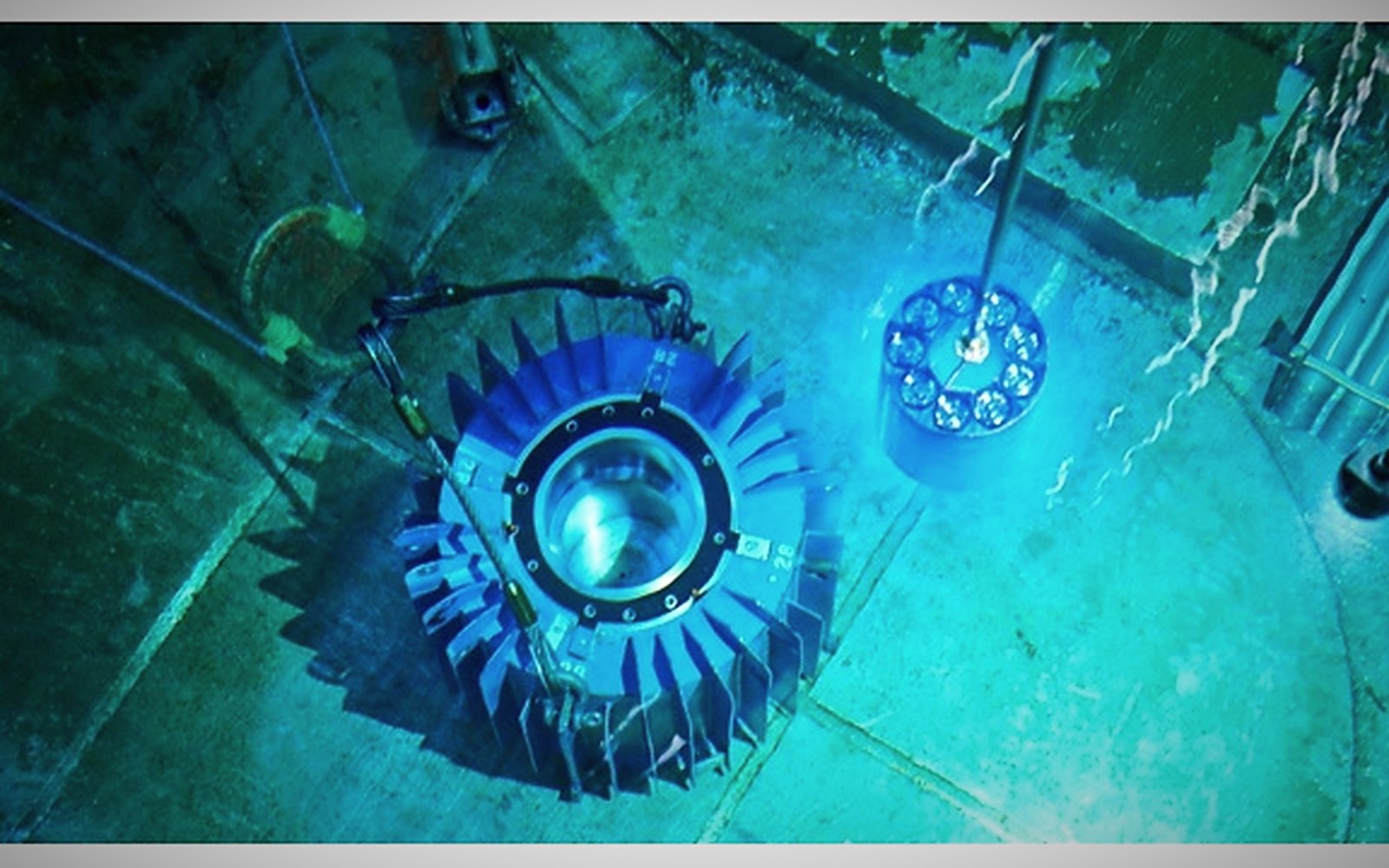 An irradiated assembly glowing blue under water in a reactor bay